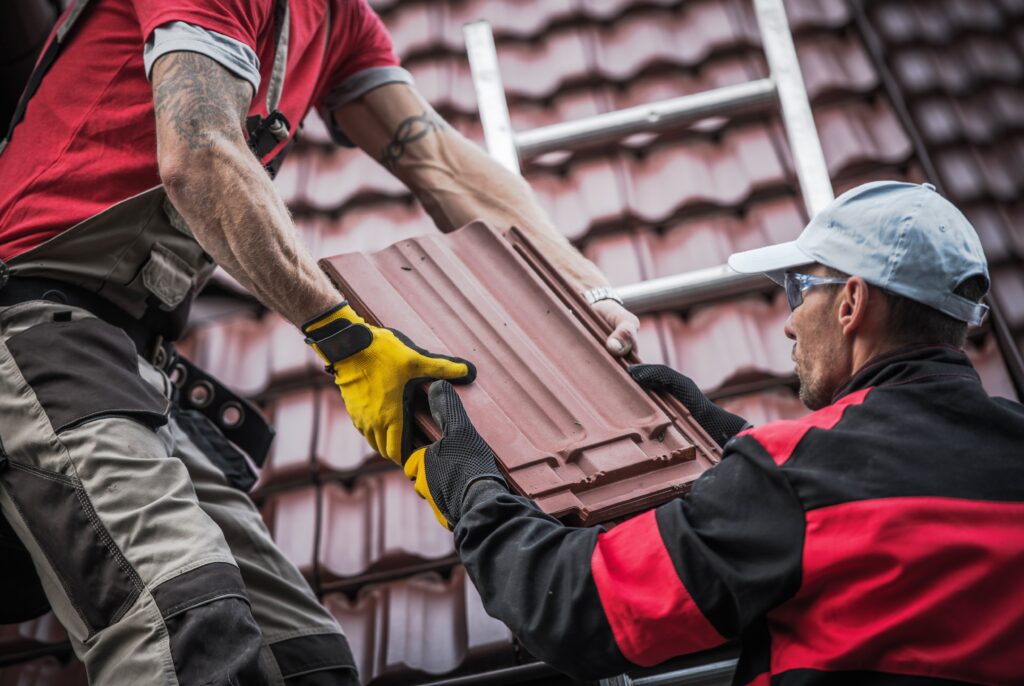 Contractors on red roof tile installation process.